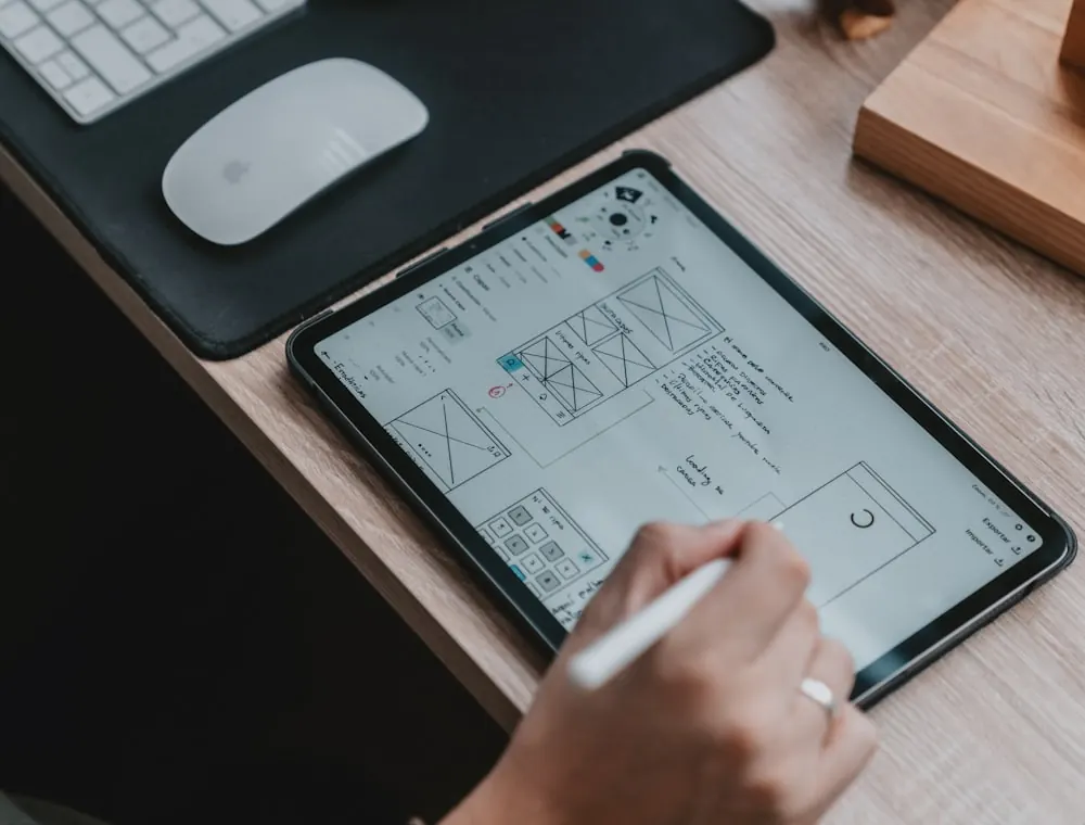Mano bocetando wireframes de una aplicación en una tablet