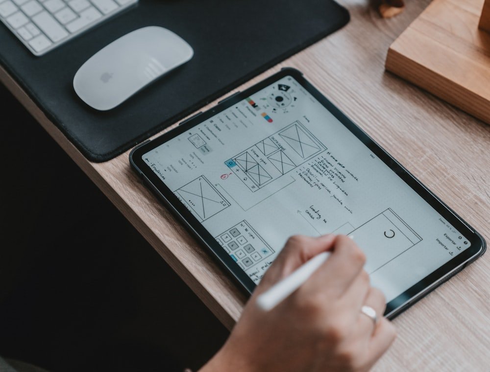 Mano bocetando wireframes de una aplicación en una tablet
